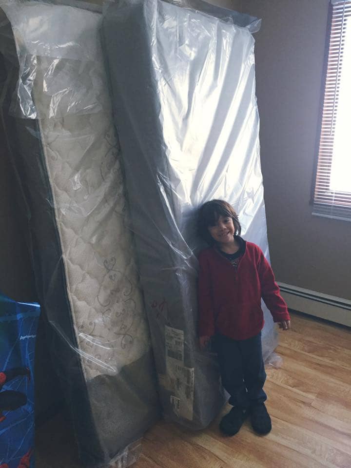 A child smiling against new donated mattresses.